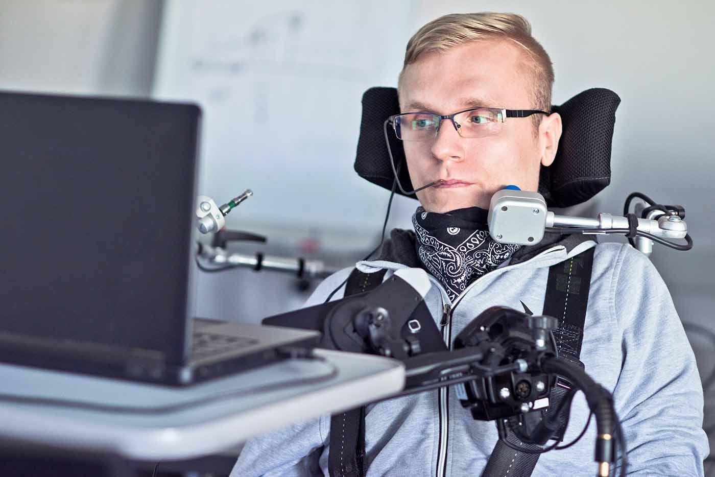 En la imagen aparece una persona con discapacidad física severa frente a un ordenador portátil. A este tipo de usuarios es que beneficia la interfaz de Navegación por sonidos de inSuit.